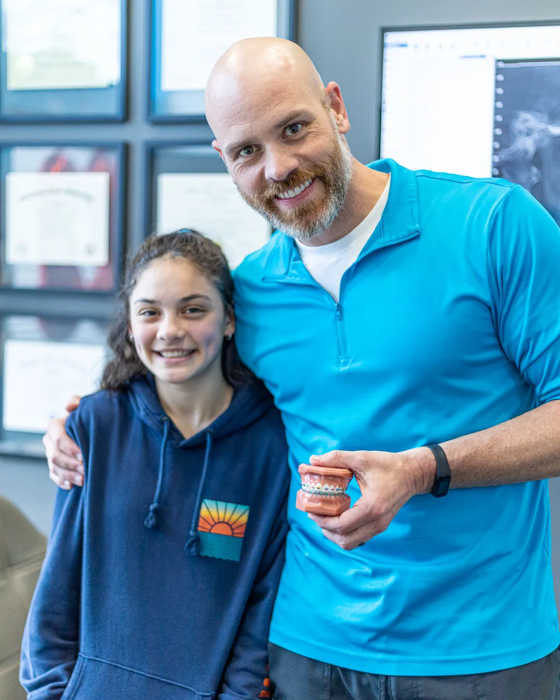 Dr. Aaron Williams with a young patient, holding a model of teeth with braces